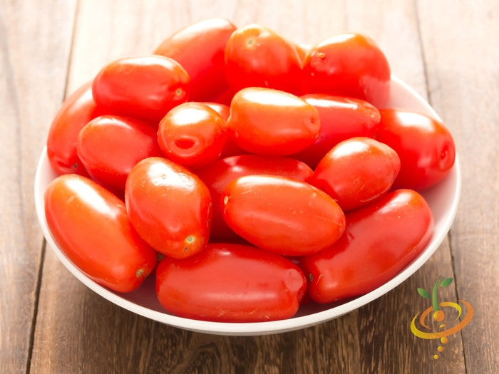 Bowl of bright red, egg-shaped Rio Grande tomatoes on wooden surface