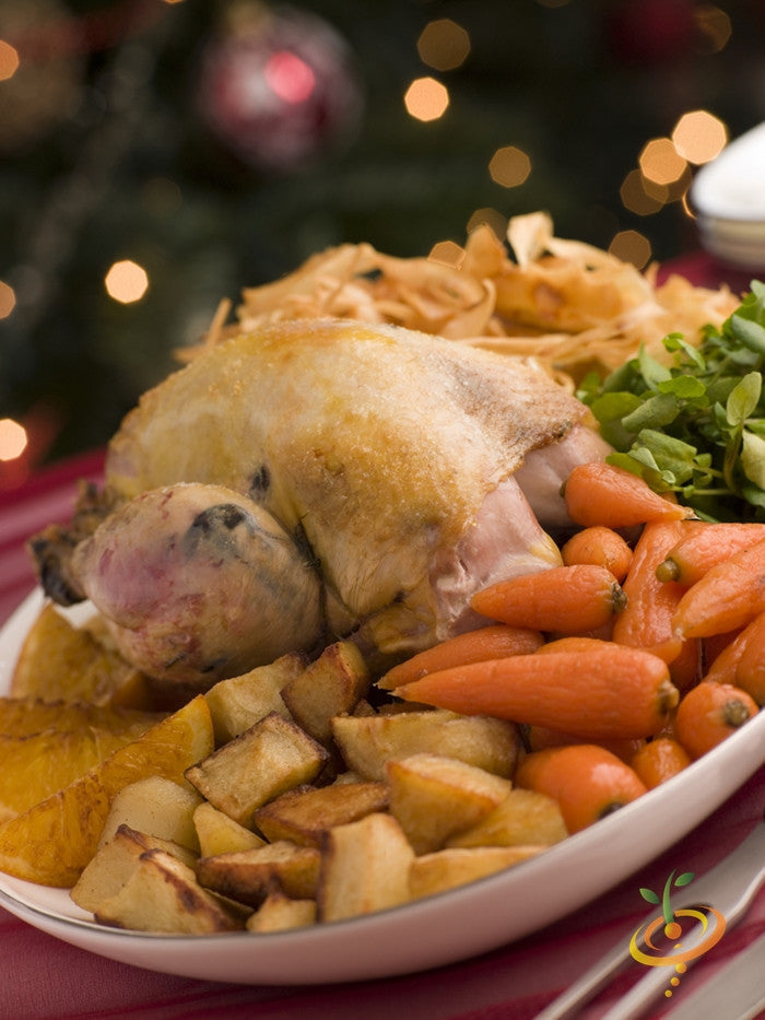 Roasted chicken with golden potatoes and cooked baby carrots on a white plate