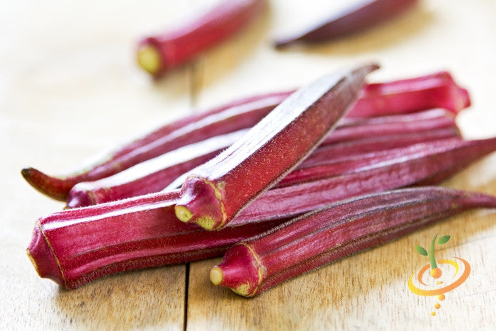 Fresh red burgundy okra pods on a wooden surface, showcasing vibrant color and texture