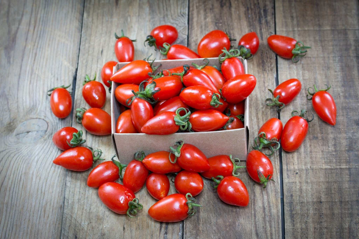 Tomato - San Marzano Seeds Close-up of fresh red San Marzano tomatoes spilling out of a small cardboard box on a wooden surface
