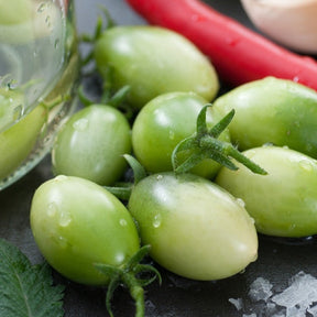 Green Grape indeterminate tomato seeds from SeedsNow, showing vibrant green grape-shaped tomato clusters on the plant.